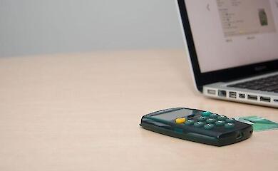 Taschenrechner, Bankkarte und ein Laptop auf dem Schreibtisch.