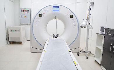 Ein Computertomograph mit ausfahrbarem Tisch in einem leeren Raum f&uuml;r medizinische Bildgebung